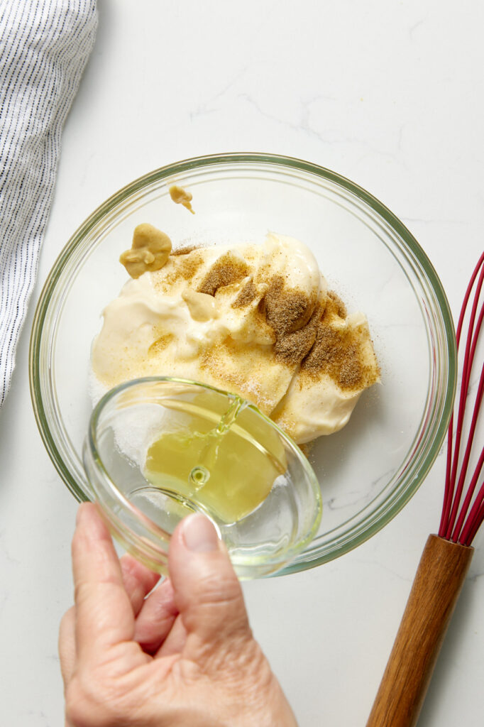 pouring the pickle juice into the mayonnaise dressing mixture