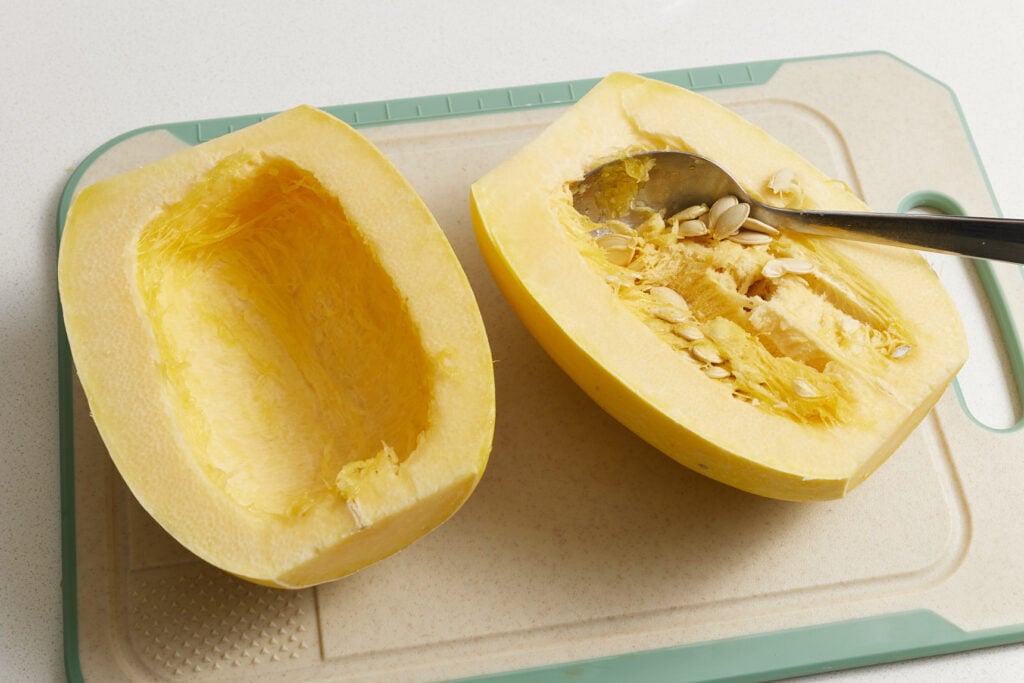Scooping the seeds and fiber out of the center of the squash halves 