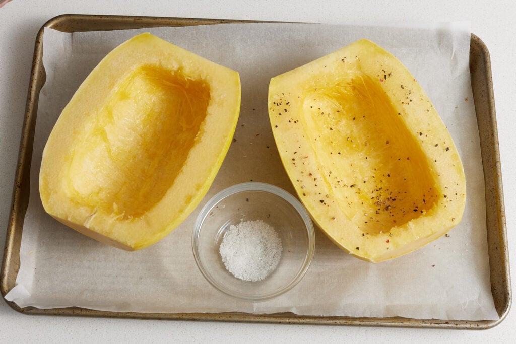Sprinkling salt and pepper over the oiled squash